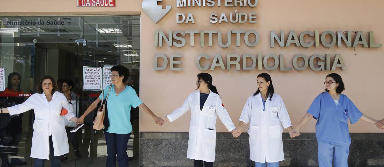 Membros do Sindsprev-RJ e funcionários do Instituto Nacional de Cardiologia(INC) dão abraço simbólico ao prédio da unidade de saúde (Foto: Pablo Jacob / Agência O Globo)