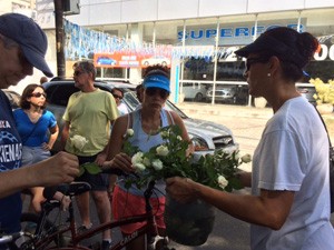 Parentes e amigos de Alex distribuem flores durante a manifestação (Foto: Guilherme Brito / G1)