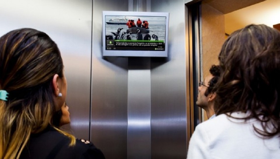 Transmissão da programação da Elemidia em elevador de prédio comercial. Foto: Divulgação/Pin It